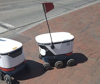 213 waiting behind another food delivery robot to cross the street