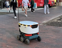 213 on a brick road in front of a few people and food trucks